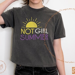 May include: A dark gray cropped t-shirt with a yellow sun graphic and the text "NOT GIRL SUMMER" in purple and yellow lettering.
