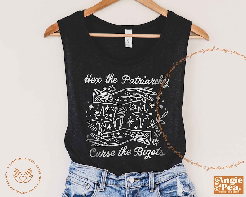 Może przedstawiać: Czarny top na ramiączkach z białym nadrukiem graficznym, na kt&oacute;rym widnieje napis "Hex the Patriarchy" i "Curse the Bigots". Grafika przedstawia dłoń z okiem, zębem i gwiazdą.
