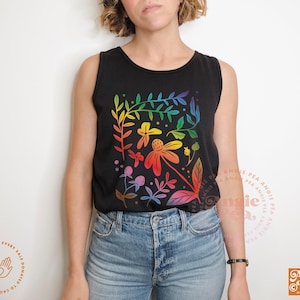 May include: Black tank top with a colorful floral design. The graphic features rainbow-colored flowers and leaves. The tank top is paired with blue jeans. The image also includes the text "Angie Pea Original Design".
