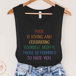 Puede incluir: Camiseta de tirantes negra con letras arco&iacute;ris que dicen "Pride is loving and celebrating yourself, despite those determined to hate you."