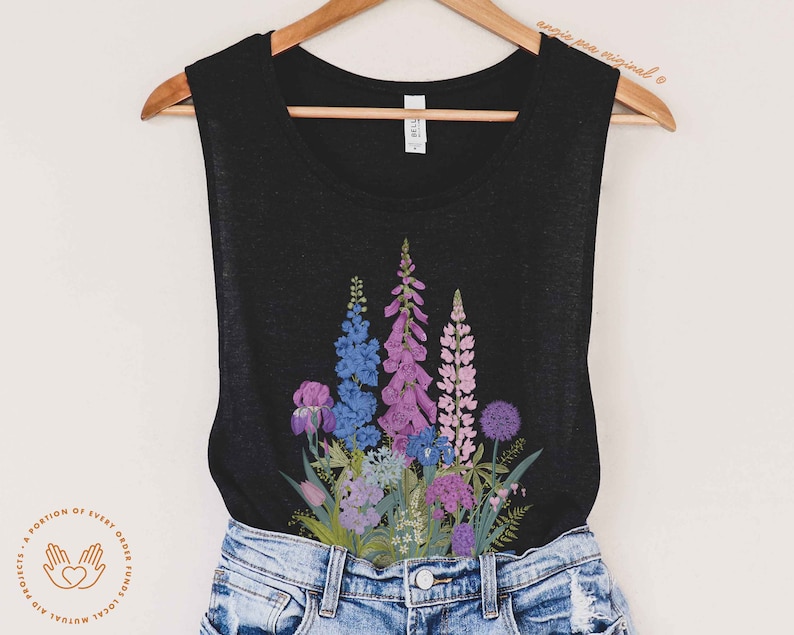 Puede incluir: Un top negro de tirantes con un estampado floral con flores moradas, azules y rosas. Las flores est&aacute;n dispuestas en forma de ramo y se centran en la parte delantera del top.