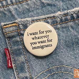 May include: A round, off-white button with the text "i want for you whatever you want for immigrants" in black lettering. The button is on a blue denim pocket. The Levi's tag is visible.