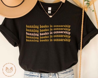 May include: Black t-shirt with the text "banning books is censorship" repeated five times in a retro font. The text is in brown and pink.