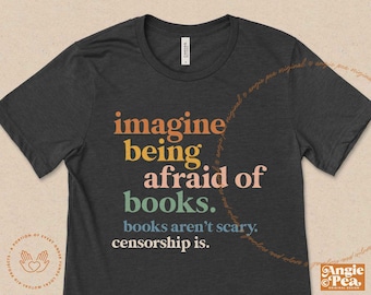 Puede incluir: Una camiseta gris oscuro con el texto "imagine being afraid of books. books aren't scary. censorship is." en letras de arcoíris de colores.