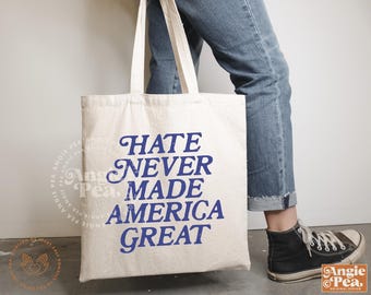 May include: A white canvas tote bag with blue text that reads "Hate Never Made America Great".
