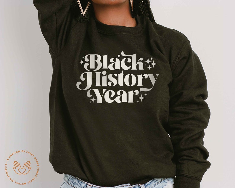 K&ouml;nnte beinhalten: Dunkel olivgr&uuml;nes Sweatshirt mit dem Text "Black History Year" in wei&szlig;er Retro-Schrift. Der Text ist von Sternen umgeben. Das Sweatshirt hat einen Rundhalsausschnitt.