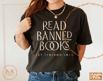 May include: A black t-shirt with the text "READ BANNED BOOKS" in gold lettering. The text "LET FREEDOM READ" is printed below in rainbow colors.