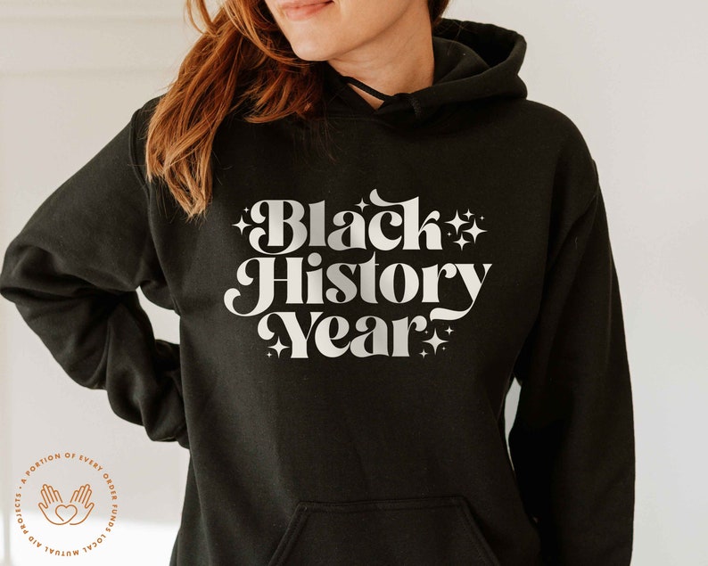 K&ouml;nnte beinhalten: Schwarzer Kapuzenpullover mit dem Text "Black History Year" in wei&szlig;er Retro-Schriftart mit Sternen. Der Hoodie hat eine Vordertasche und eine Kapuze mit Kordelzug.