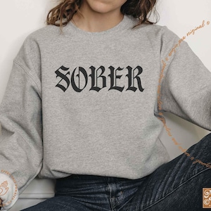 May include: A gray sweatshirt with the word "SOBER" printed in black gothic lettering.