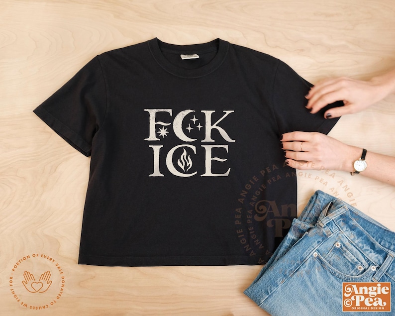 May include: Black t-shirt with the text "FCK ICE" in a distressed white font. The design includes a star, crescent moons, and a flame. The shirt is paired with blue jeans.