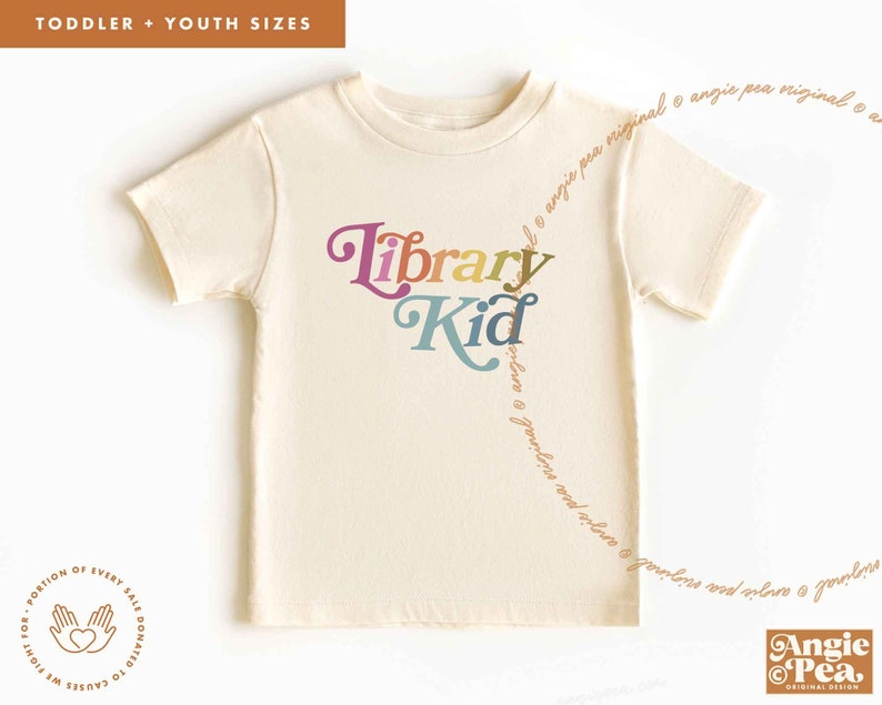 May include: A cream colored t-shirt with the text "Library Kid" in rainbow colors. The text is in a playful font. A portion of every sale is donated to causes we fight for.