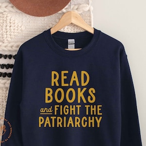 May include: Navy blue sweatshirt with the text "READ BOOKS and FIGHT THE PATRIARCHY" in yellow.