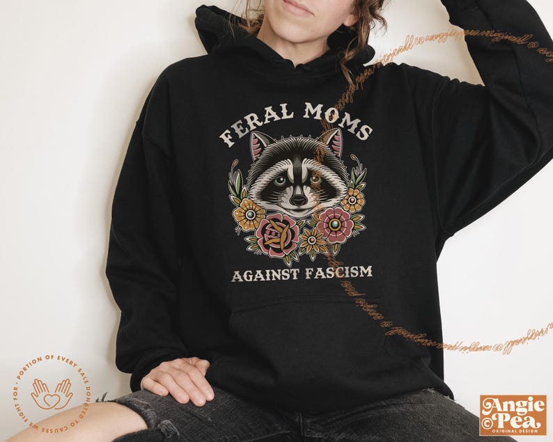 May include: Black hooded sweatshirt with a graphic of a raccoon with flowers and the text "Feral Moms Against Fascism".