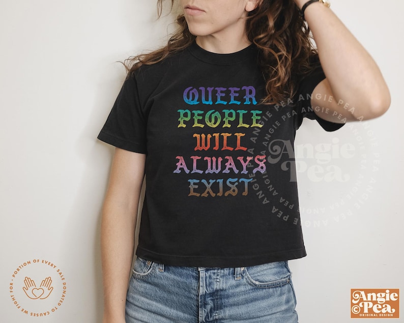 May include: A black cropped t-shirt with the text "Queer People Will Always Exist" in rainbow colors. The text is in a gothic font.