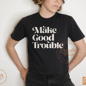 May include: A black t-shirt with white text that reads "Make Good Trouble".