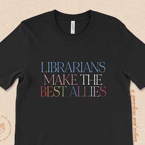 Puede incluir: Camiseta negra con el texto "LIBRARIANS MAKE THE BEST ALLIES" en colores arco&iacute;ris.