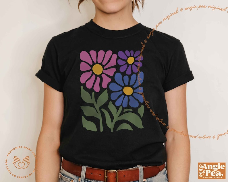 May include: A black t-shirt with a floral design featuring pink, purple, and blue flowers with yellow centers. The flowers are stylized and have a retro feel.