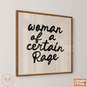 May include: A framed print with the words "woman of a certain Rage" in black script. The artwork has a beige background and a brown wooden frame. The lower right corner has the Angie Pea logo.