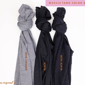 May include: Three muscle tank tops in different colors: asphalt slub, black, and black slub. The tank tops are folded and tied in a knot.