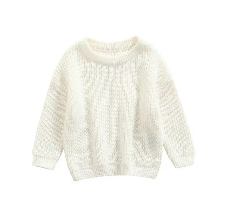 May include: A cream-colored, knitted sweater with a crew neck and long sleeves. The sweater has a ribbed texture and a relaxed fit. This cozy knitwear is suitable for casual wear.