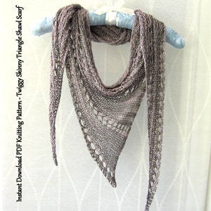 May include: A delicate, hand-knitted triangle shawl in a soft, variegated purple and gray yarn. The shawl is draped over a blue hanger and has a lacy, openwork pattern.
