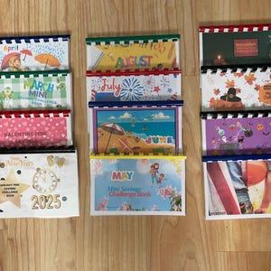 May include: A set of 12 colourful monthly mini savings challenge books with a variety of themes, including holidays, seasons, and animals. Each book has a different design and features a title with the month of the year.