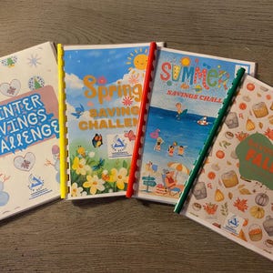 May include: Four colourful spiral bound notebooks with seasonal themes: Winter Savings Challenge, Spring Saving Challenge, Summer Savings Challenge, and Savings Fall. Each notebook has a different design and colour scheme.