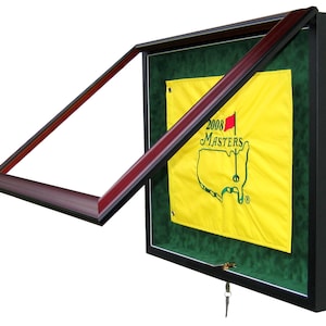 May include: A black and mahogany wood framed display case with a glass front and a key lock. The case is open and displays a yellow golf flag with the text "2008 Masters" and a green outline of the United States.