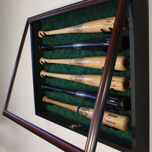 May include: A wooden baseball bat display case with a dark brown frame and a green felt interior. The case is open and five bats are displayed inside. The bats are all wooden and have different logos and brands.