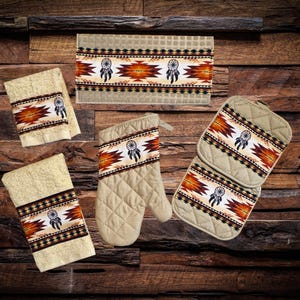 May include: Set of kitchen towels and pot holders with a Native American dreamcatcher design. The towels and pot holders are beige with brown, orange, and black accents. The design features a dreamcatcher with feathers and geometric patterns.