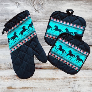 May include: Set of three black quilted kitchen pot holders with a turquoise and pink geometric pattern featuring a silhouette of running horses.