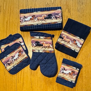 Puede incluir: Conjunto de toallas de cocina y agarraderas azules con un diseño de caballos. Las toallas y agarraderas presentan un patrón multicolor de caballos corriendo sobre un fondo marrón y naranja.