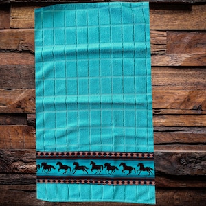 Könnte beinhalten: Ein türkisfarbenes Geschirrtuch mit einem karierten Muster und einem Rand aus schwarzen Pferden, die am unteren Rand entlanglaufen.