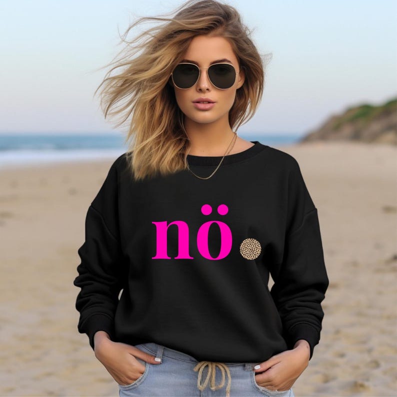 May include: Black sweatshirt with the word "n&ouml;." in bright pink, featuring two pink dots above the "n" and a leopard print dot. The sweatshirt is worn by a person wearing sunglasses and a gold necklace.