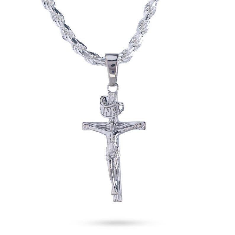 May include: A silver-colored crucifix pendant with a detailed depiction of Jesus on the cross, suspended from a matching rope chain. The pendant features the inscription "INRI" above the cross. The chain and pendant are made of a shiny, reflective metal.