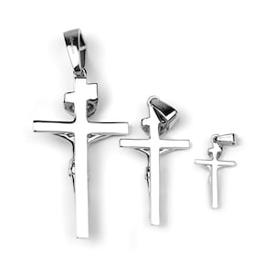May include: Three silver crucifix pendants of varying sizes are displayed against a white background. Each pendant features a detailed depiction of Jesus on the cross. The pendants are designed with a polished finish, reflecting light.