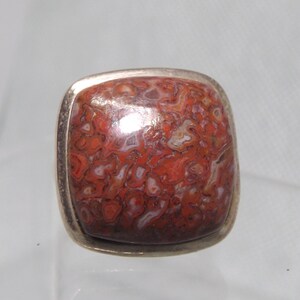May include: A square-shaped ring with a red and white agate stone set in a silver bezel.