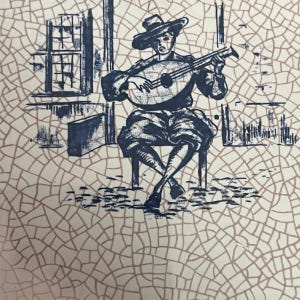 May include: A decorative plate with a blue and white illustration of a musician playing a lute. The musician is seated on a chair, wearing a hat and period clothing. The background features architectural elements.