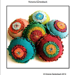May include: The image displays a tutorial pattern called "Boro Bobbles" by Victoria Gertenbach. It showcases several colourful, round fabric ornaments with embroidered details. The ornaments are in shades of red, green, blue, and yellow, with intricate stitching.