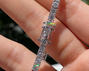 May include: A silver tennis bracelet with a clasp closure. The bracelet is set with small, round, clear diamonds.