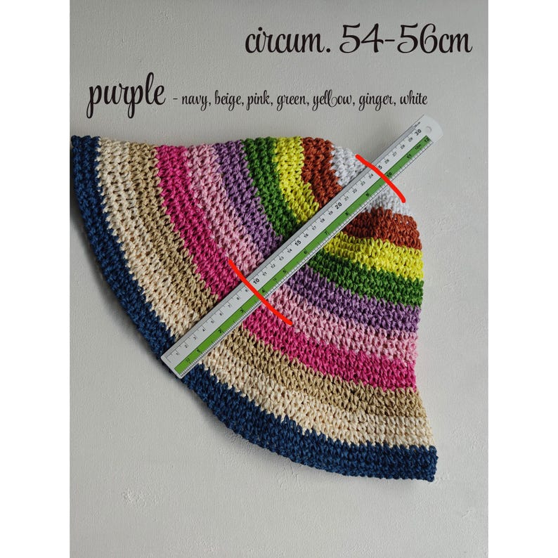 May include: A crocheted hat in a rainbow of colors, including navy, beige, pink, green, yellow, ginger, and white. The hat's circumference is 54-56cm. The word "purple" is written above the hat.