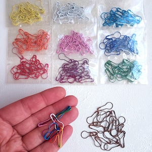 Pode incluir: Uma coleção de marcadores de ponto coloridos em várias tonalidades, incluindo amarelo, prata, azul, laranja, rosa, roxo, vermelho, verde e castanho. Alguns marcadores são embalados em sacos de plástico transparentes, outros são segurados em uma mão.