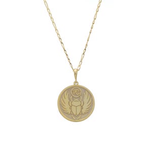 Round medallion necklace with an embossed scarab beetle surrounded by rays, hanging from a fine cable chain. Photographed on a white background, the pendant celebrates ancient Egyptian symbolism and rebirth. Available in solid 14K gold, gold vermeil or 925 sterling silver with gold plated or rose gold plated finishes. Comes with chain lengths 16–24 inches and can be personalized on the back with initials, dates or affirmations to create a meaningful talisman.
