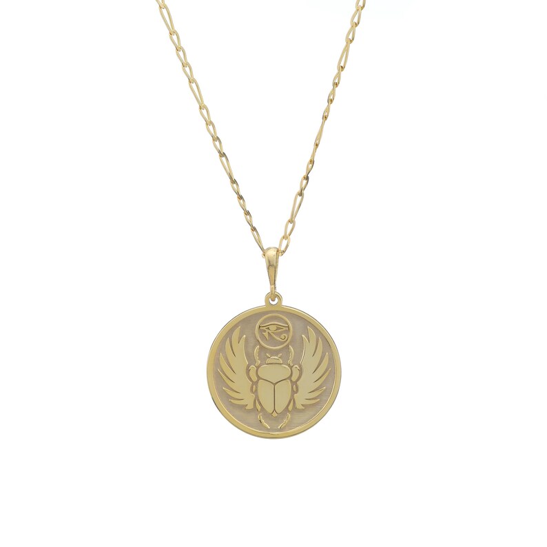 Round medallion necklace with an embossed scarab beetle surrounded by rays, hanging from a fine cable chain. Photographed on a white background, the pendant celebrates ancient Egyptian symbolism and rebirth. Available in solid 14K gold, gold vermeil or 925 sterling silver with gold plated or rose gold plated finishes. Comes with chain lengths 16–24 inches and can be personalized on the back with initials, dates or affirmations to create a meaningful talisman.
