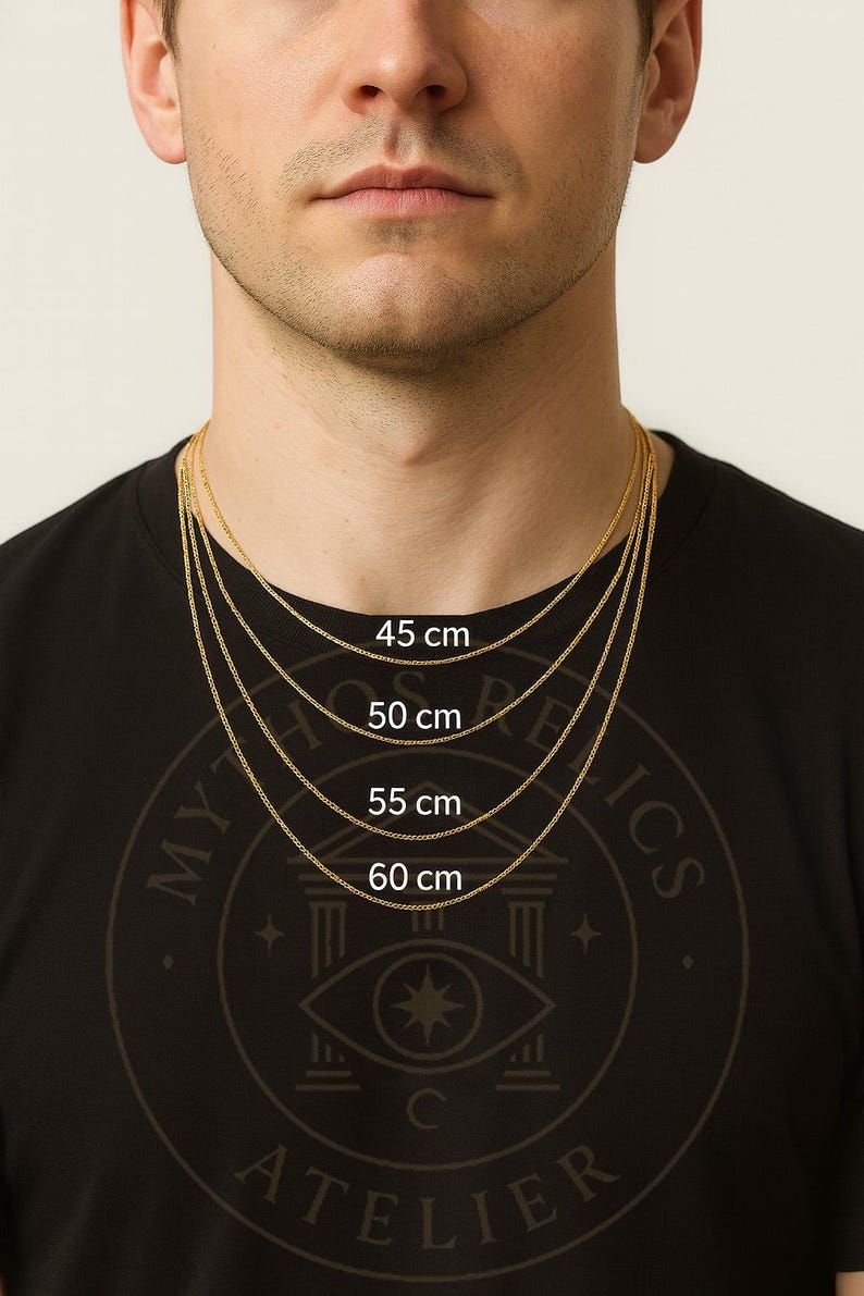 K&ouml;nnte beinhalten: Ein Mann tr&auml;gt ein schwarzes T-Shirt mit goldenen Halsketten in verschiedenen L&auml;ngen: 45 cm, 50 cm, 55 cm und 60 cm. Die Halsketten werden vor einem hellen Hintergrund pr&auml;sentiert. Das T-Shirt tr&auml;gt den Text "MYTHICS ATELIER".