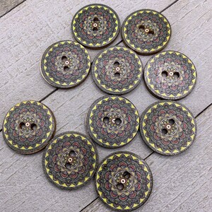 May include: Ten round wooden buttons with a mandala design in shades of yellow, red, black, and green. The buttons have two holes each.