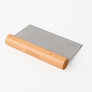 May include: A wooden handled stainless steel dough scraper with the text "JL Gentry Handcrafted" engraved on the handle.