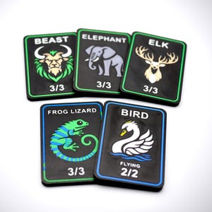 May include: Five black cards with animal illustrations and text. The cards feature a beast, elephant, elk, frog lizard, and bird. Each card has a colored border and numerical values. The bird card also has the word "flying".