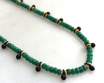 May include: A green gemstone necklace with black beads and gold accents. The necklace is made of small, faceted beads and has a simple, elegant design.