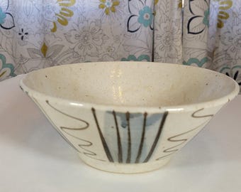 May include: A white ceramic bowl with a speckled glaze and a blue and brown abstract design.